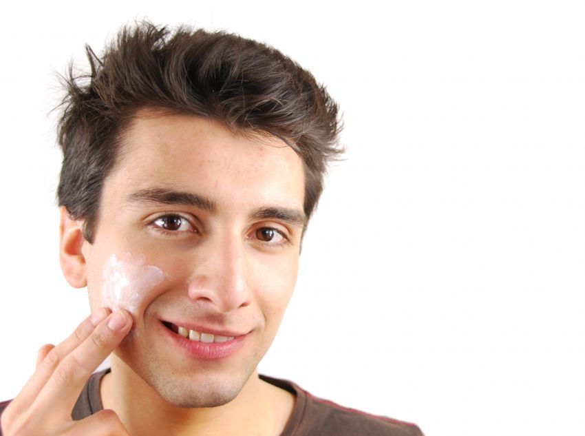 Smiling man applying face cream