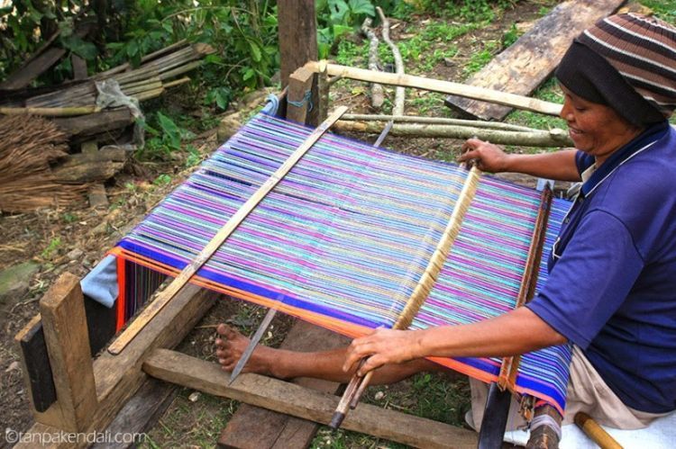 Seorang ibu sedang menenun kain songke