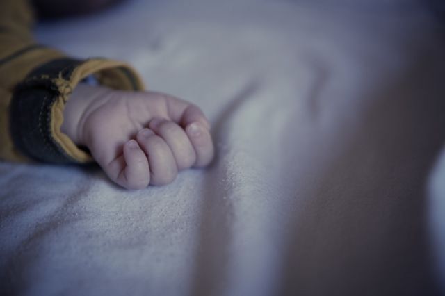 Baby in Yellow and Black Long Sleeved Shirt Lying on White Textile