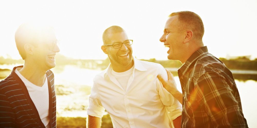 Gay couple in discussion with friend at sunset