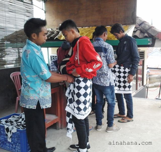 Pemakaian kain Saput Poleng sebelum masuk ke area candi