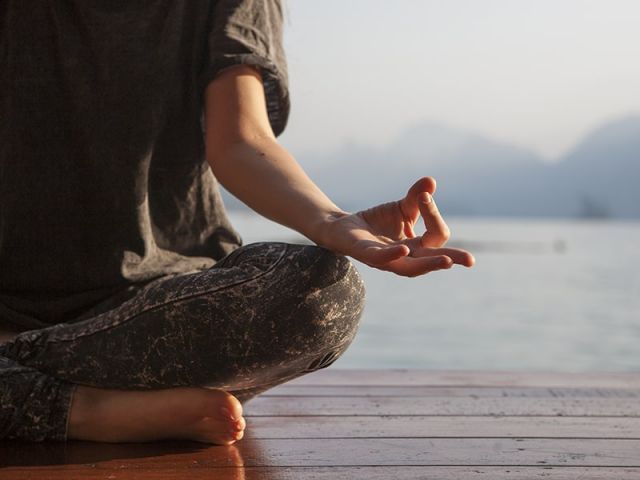 Woman practicing yoga by a lake