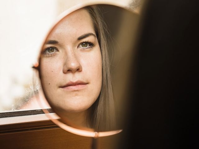 Woman looking at her face in mirror