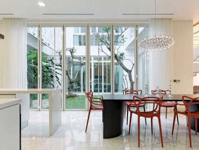 Ruang makan serba putih dengan sentuhan merah, hunian Green Garden Residence karya Atelier Cosmas Gozali