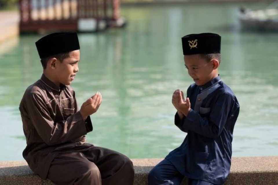 40 Ucapan Hari Santri Nasional 2026 untuk story WA, Penuh Doa sampai yang Kocak 8 Dua anak laki-laki berpakaian muslim berdoa bersama di tepi kolam