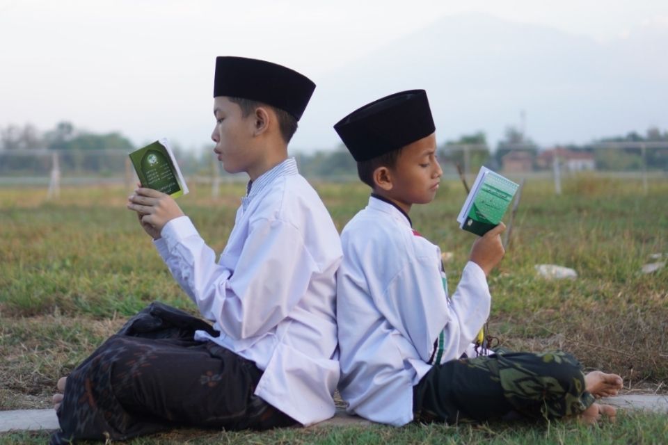 40 Ucapan Hari Santri Nasional 2026 untuk story WA, Penuh Doa sampai yang Kocak 7 Dua santri cilik duduk membelakangi sambil membaca buku di area terbuka