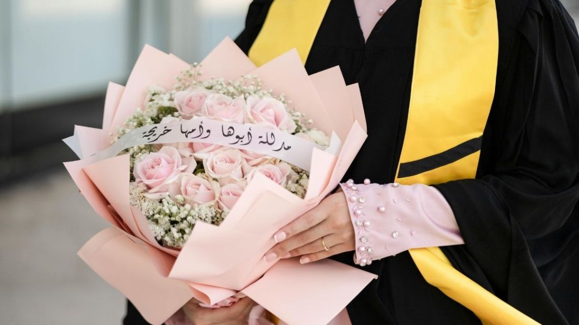 40 Ucapan Selamat Wisuda untuk Sahabat dan Pacar yang Paling Relate & Nggak Pasaran 7 Wisudawati memegang buket bunga mawar pink