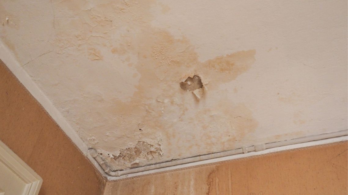 Dinding rumah dengan noda rembesan air dan cat mengelupas