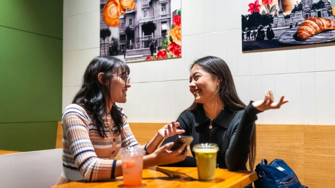 5 Fakta Bahasa Campur-Campur tapi Tetap Indonesia, Gen Z Relate Banget! 7 Dua perempuan muda mengobrol santai di kafe